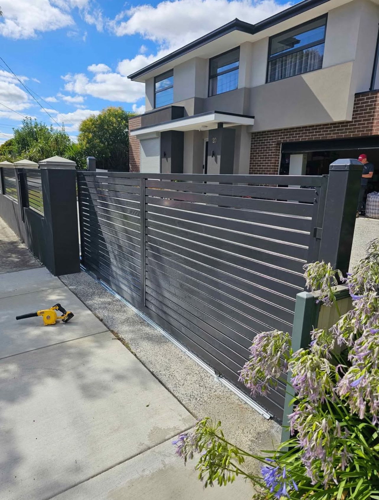 Grey aluminium slat sliding gate in front of a two-storey home, Werribee